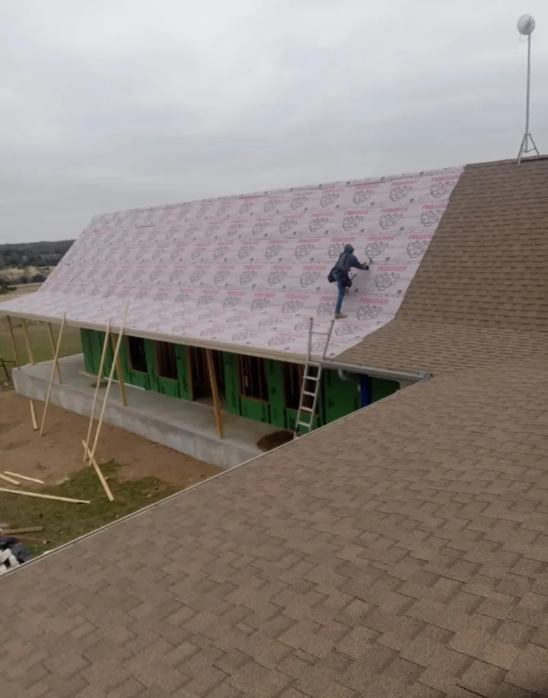 Worker preparing underlayment for a metal roof installation in Grimes